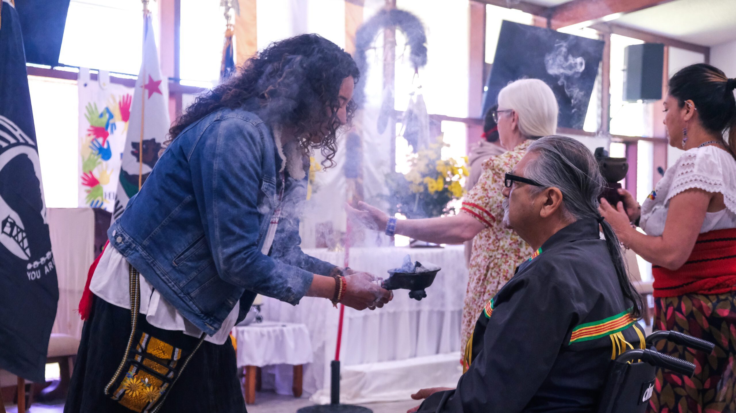 Traditional healing ceremony with community members participating in a smudging ritual