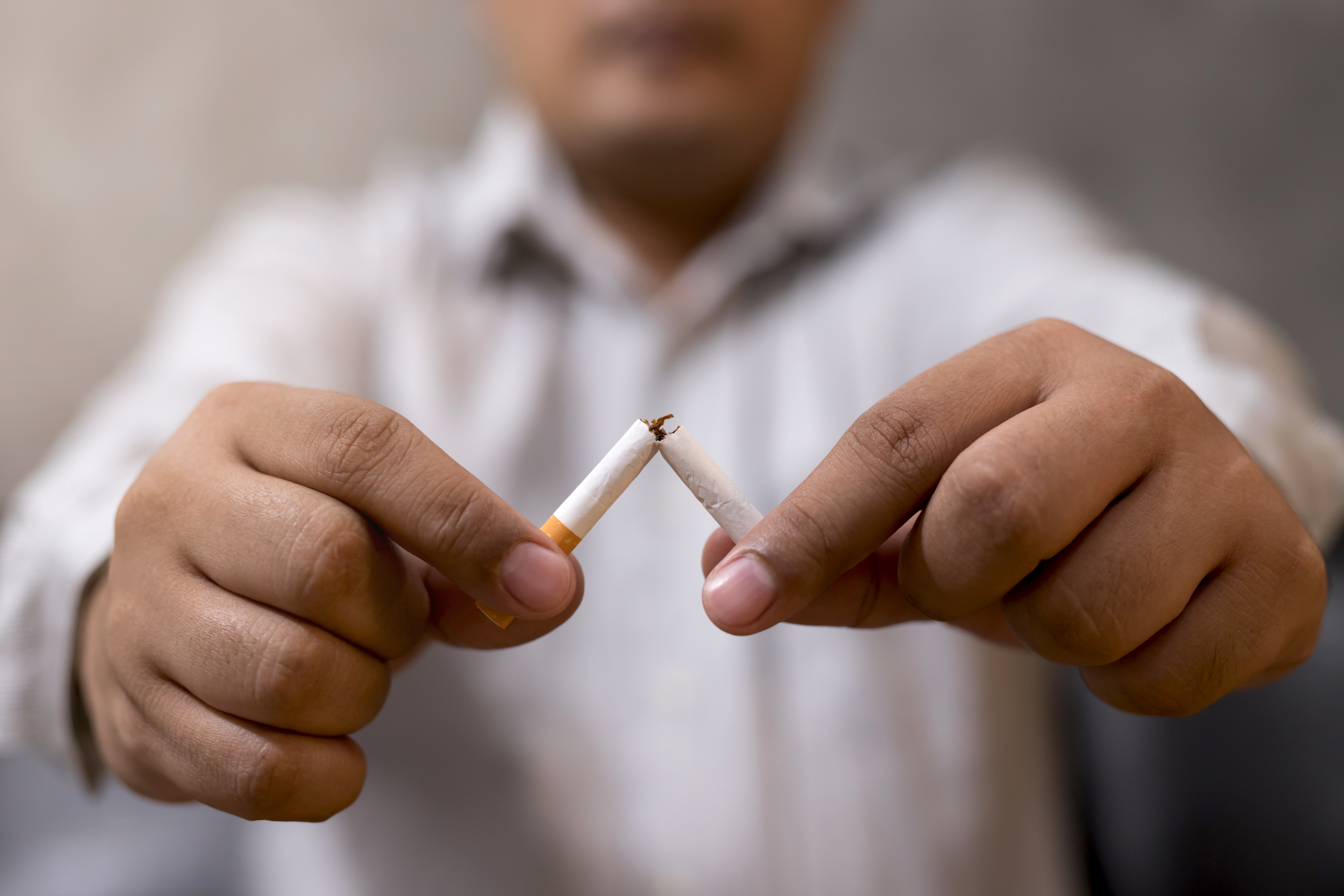 Person breaking cigarette for tobacco cessation